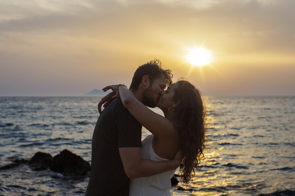 Greece Destination Engagement - Corfu - couple kissing with sunset background in Loggas Beach