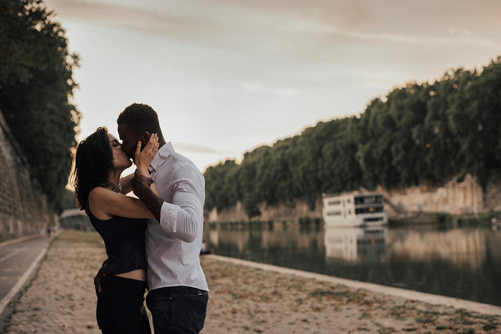 Interracial couple kissing, along the river Tiber