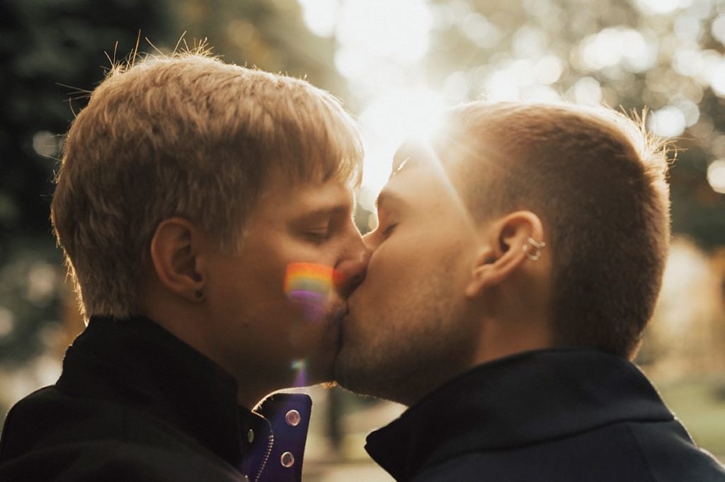 Belgium Wedding Photographer - Gay couple kissing with a strong dawn light and a rainbow flare